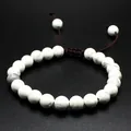 Macro detail of a handmade 8mm white natural stone bead bracelet with adjustable cord. - Howlite