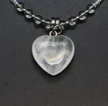 Close-up detail of clear heart-shaped stone pendant with iridescent bead chain. - White Crystal