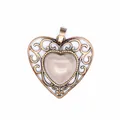 Detail of vintage bronze-tone heart pendant featuring intricate filigree and central pink stone - Rose Quartz