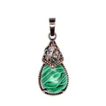 Detailed view of a vintage teardrop green stone pendant with ornate bronze filigree. - Malachite