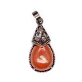 Macro detail of retro teardrop-shaped red agate pendant with ornate bronze filigree - Red Jasper
