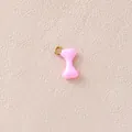 Detailansicht eines rosa emaillierten Knochenanhängers mit vergoldetem Ring für DIY-Schmuck - Rosa Knochen