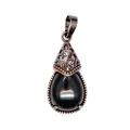 Macro view of a teardrop black agate pendant with vintage bronze filigree detail - Obsidian