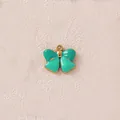 Detailansicht eines türkisfarbenen Emaille-Schleifenanhängers mit Goldrand für DIY-Schmuck - Grüne Schleife