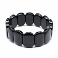 Close-up of polished black natural stone beads on a minimalist hand plate bracelet - Obsidian