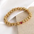 Close-up detail of 8mm gold stainless steel beaded bracelet featuring a red birthstone gem - 8mm Bead / July (NA21-8 Red)