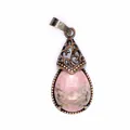 Close-up of vintage pink teardrop stone pendant with bronze filigree detail. - Rhodonite