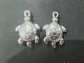 Detail von zwei silbernen Meeresschildkröten-Anhängern aus Edelstahl für DIY-Schmuck - 28.8*18.83*6.99mm