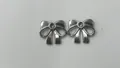 Detailopname van twee zilveren roestvrijstalen strikhangers voor DIY-sieraden maken. - Strik Hanger (HY-587) / 9.2x10.7x2.55mm (Gat 1.9mm) / Staalkleur