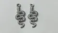 Detailed view of two silver stainless steel snake-shaped charms for jewelry making. - 25.85x9.4x1.95mm