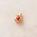 Gros plan d'une perle de lapin dorée avec un cœur rouge et un nœud rose détaillé - Tête de Lapin Rouge
