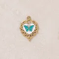 Primo piano di ciondolo a cuore dorato con dettaglio farfalla in smalto turchese - Farfalla Cuore / Blu