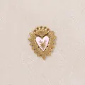 Primo piano di un ciondolo a cuore in acciaio inossidabile dorato con smalto rosa - Cuore con Corona / Rosa