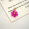 Detailed macro view of a pink crystal flower pendant with gold-plated wire wrapping. - 13mmx10mmx3.5mm / Rose Red