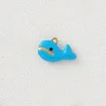 Detailed macro view of a cute blue enamel whale charm with gold-plated stainless steel edges - Blue Whale