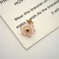 Macro view of pink crystal flower pendant with gold-plated stainless steel wire detail - 13mmx10mmx3.5mm / Pink White