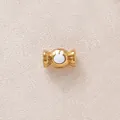 Makroansicht einer vergoldeten Bonbon-Perle mit weißem Tropföl-Hasenmotiv. - White Candy