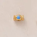 Vue macro d'une perle dorée en forme de bonbon avec un motif de lapin en émail bleu - Bonbon Bleu