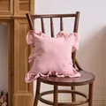 Elegant French ruffle pillowcase in soft pink displayed on a classic vintage wood chair - Pink