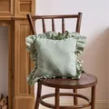 Elegant sage green French style ruffle cushion cover displayed on a rustic wooden chair - Bean Green