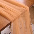 Elegant apricot orange sheer tulle fabric draped on wooden table for event decoration - Orange