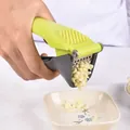 Manual garlic press tool featuring an ergonomic green handle and efficient grey crusher - Manual Garlic Press (021082) / Stainless Steel Mesh and Plastic Handle / Fruit Green and Dark Gray