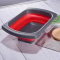 Collapsible red and grey rectangular colander with extendable handles for kitchen sink. - Red