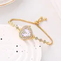 Dettaglio di un orologio a cuore dorato con strass e cinturino a scorrimento regolabile. - Oro