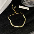 Nahaufnahme eines eleganten verstellbaren Goldarmbands mit opalisierenden Kristallen - Strass Schiebearmband / Himmelblau