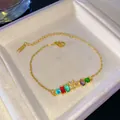 Detalle de una pulsera dorada con gemas de colores y una letra Y decorada con brillantes - Letra Y