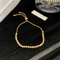 Nahaufnahme eines vergoldeten Armbands mit zarten rosa und weißen Zirkonsteinen. - Hellrosa Weiß