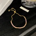 Detailansicht eines eleganten, verstellbaren Goldarmbands mit funkelnden rosa Kristallen - Rosa Weiß