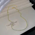 Elegante vergoldete Halskette mit runden hellblauen Kristallen auf Schmucktablett - Hellgrün