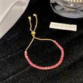 Nahaufnahme eines eleganten goldfarbenen Armbands mit funkelnden rosa Kristallen und Verschluss - Strass Schiebearmband / Rosa