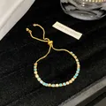 Nahaufnahme von hellblauen und klaren Kristallsteinen auf einem vergoldeten Bolo-Armband - Blassbläuliches Weiß