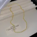 Elegant gold necklace with pale yellow imitation zircons displayed on a beige tray - Creamy White