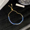 Nahaufnahme eines goldfarbenen verstellbaren Armbands mit blauen Kristallen - Blau