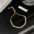 Eleganzes goldfarbenes verstellbares Tennisarmband mit brillant funkelnden Kristallsteinen - Gebrochenes Weiß