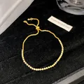 Nahaufnahme eines luxuriösen vergoldeten verstellbaren Armbands mit glitzernden Zirkonia - Feines Blasses Ecru