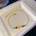 Pulsera ajustable dorada con pedrería de colores arcoíris y un dije brillante letra E - Letra E