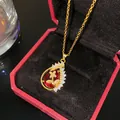 Primer plano de un colgante de lágrima bañado en oro con una piedra roja y circonitas claras. - Gota de Agua Pez Dorado Piedra Roja