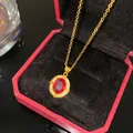 Vue détaillée d'un élégant collier en or avec pendentif rubis dans un écrin rouge - Palais Pierre Rouge Ovale