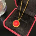 Gros plan d'un collier de style vintage avec pendentif rond rouge dans un écrin rouge - Disque Vintage Pierre Rouge
