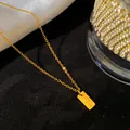 Gros plan d'un collier minimaliste en acier titane plaqué or avec la lettre T - Lettre T / Or