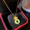 Primer plano de un collar dorado con colgante de imitación jade en estuche rojo. - Lazo Hebilla Ping'an (W1161)