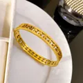 Detail view of a luxury golden stainless steel hollowed four-leaf clover pattern bangle - Hollow Meander Clover / Gold
