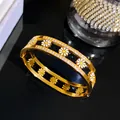 Detailopname van een gouden madeliefje armband van titanium staal met glinsterende steentjes - Holle Madeliefje Bloem Armring / Goud