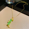 Dettaglio di una collana con pendente in bambù dorato, pietre verdi e accenti in cristallo - Catena d'Oro con Pendente in Bambù Verde