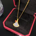 Élégant collier en or avec un pendentif blanc en forme d'éventail et une pierre rouge - Style de Feuille de Ginkgo en Éventail