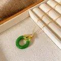 Close-up detail of golden titanium steel necklace with crown charm and green round pendant - Crown Pingan Buckle Style (W124)